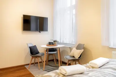 a room with a table and chairs and a tv on the wall at Malila Premium Apartments Cracow Traugutta in Kraków