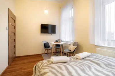 a bedroom with a bed and a table with chairs at Malila Premium Apartments Cracow Traugutta in Kraków
