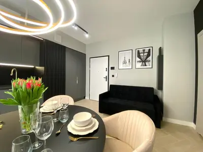 a living room with a table with chairs and a black couch at Apartament przy Rakowickiej II Old Town in Kraków