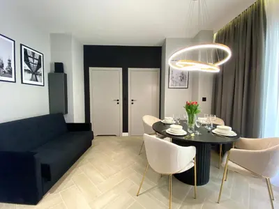 a living room with a black table and white chairs at Apartament przy Rakowickiej II Old Town in Kraków