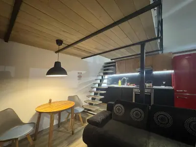 a living room with a couch and a table and stairs at Wawrzynca paradise - loft in the Kazimierz district in Kraków