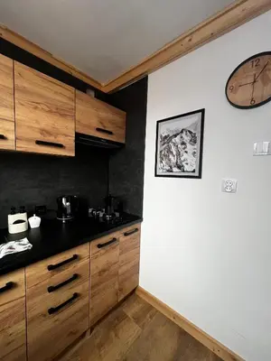 a kitchen with wooden cabinets and a clock on the wall at Apartament 