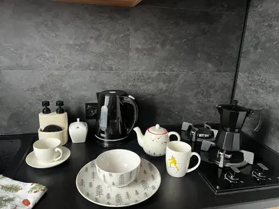 a counter top with cups and plates and a coffee maker at Apartament 