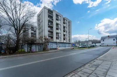 an empty street with a tall white building at Siewna Homely Apartment in Kraków