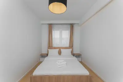 a small bedroom with a white bed and a light at Siewna Homely Apartment in Kraków