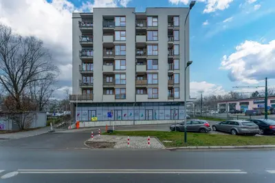a tall building with cars parked in a parking lot at Siewna Homely Apartment in Kraków
