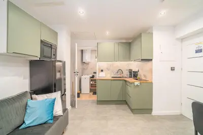 a kitchen with green cabinets and a couch at Podgórze 2-Bedrooms Apartment - 54m2, Air Con - by Rentujemy in Kraków