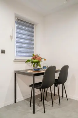 a dining room table with chairs and a window at Podgórze 2-Bedrooms Apartment - 54m2, Air Con - by Rentujemy in Kraków