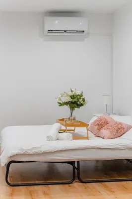 a bed with a table with a vase of flowers on it at Podgórze 2-Bedrooms Apartment - 54m2, Air Con - by Rentujemy in Kraków