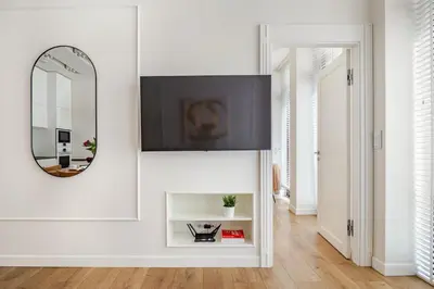 a living room with a mirror and a tv on a wall at Old Town Apt with AC & Parking, 5 min Main Sq & Kazimierz in Kraków