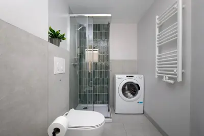 a bathroom with a toilet and a washing machine at Łagiewniki Apartments Free Parking in Kraków