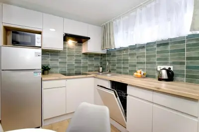 a kitchen with white cabinets and a stainless steel refrigerator at Łagiewniki Apartments Free Parking in Kraków