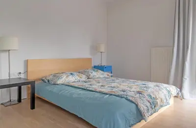 a bed with a blue comforter and a table at Castor in Kraków