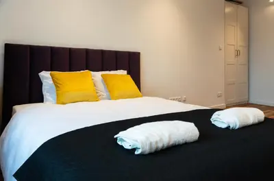 a bedroom with a large bed with two towels on it at Soniya's Castle View Apartment in Kraków