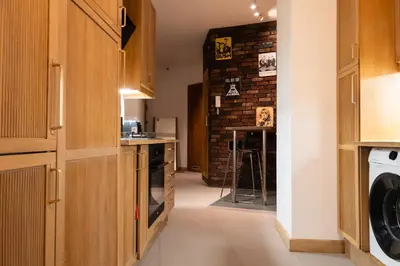 a kitchen with wooden cabinets and a brick wall at Soniya's Castle View Apartment in Kraków