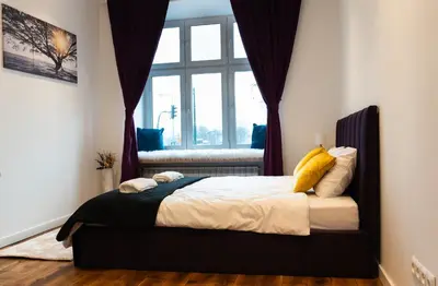 a bedroom with a bed with a window at Soniya's Castle View Apartment in Kraków