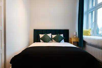 a bedroom with a bed with green and yellow pillows at Soniya's Castle View Apartment in Kraków