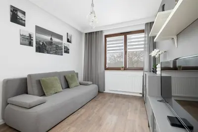 a living room with a couch and a window at White and Grey Apartment in Cracow with Parking by Noclegi Renters in Kraków