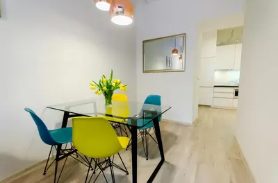 a dining room with a glass table and colorful chairs at Central Krak Apartments in Kraków