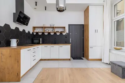 a kitchen with white cabinets and a black wall at Apartment for two - Krowoderska 21 street in Kraków