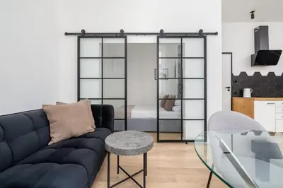 a living room with a black couch and a glass table at Apartment for two - Krowoderska 21 street in Kraków