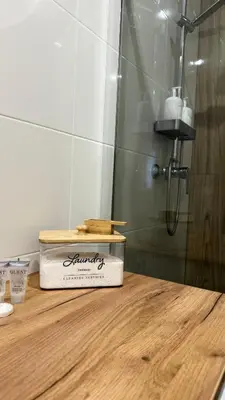 a bathroom with a shower with a wooden box on a counter at MICKIEWICZ HOUSE Apartamenty in Wadowice