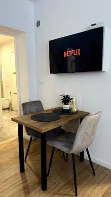 a table with two chairs and a television on a wall at MICKIEWICZ HOUSE Apartamenty in Wadowice