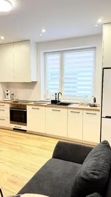 a kitchen with white cabinets and a couch in a room at MICKIEWICZ HOUSE Apartamenty in Wadowice