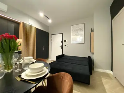 a living room with a black couch and a table at Apartament przy Rakowickiej IV Old Town in Kraków