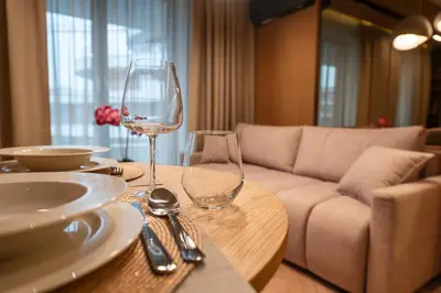 a table with two wine glasses and a couch at Fleurmont Apartment by Cracovia Prime in Kraków