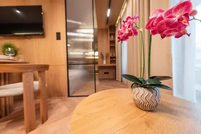 a vase with pink flowers sitting on a table at Fleurmont Apartment by Cracovia Prime in Kraków