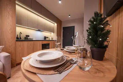 a table with plates and glasses and a christmas tree at Fleurmont Apartment by Cracovia Prime in Kraków