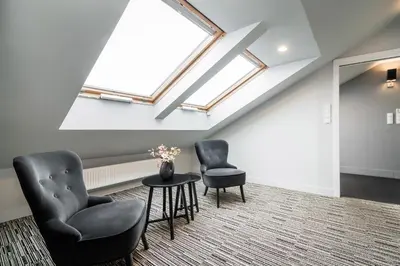 two chairs and a table in a room with a skylight at Krzyża Residence in Kraków
