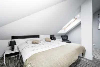 a white bedroom with a large bed and a chair at Krzyża Residence in Kraków