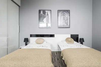 two beds in a white room with pictures on the wall at Krzyża Residence in Kraków