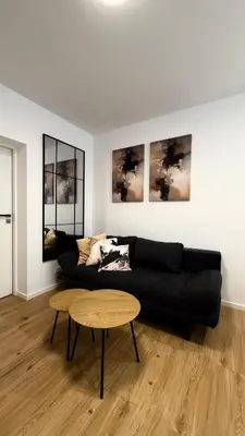 a living room with a black couch and a table at MICKIEWICZ HOUSE Apartamenty in Wadowice