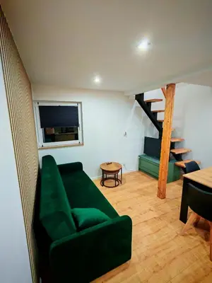 a living room with a green couch and a staircase at Beskidzka Oaza 2 in Targanice
