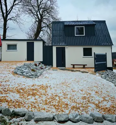 a white house with a black roof and a bench at Beskidzka Oaza 2 in Targanice