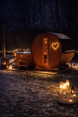 a large wooden cabin with candles in the snow at night at Pod Łopieniem z Sauną i Balią in Tymbark