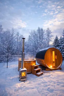 a wooden igloo with a wood stove in the snow at Pod Łopieniem z Sauną i Balią in Tymbark