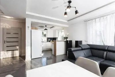 a living room with a black couch and a kitchen at Pod Łopieniem z Sauną i Balią in Tymbark