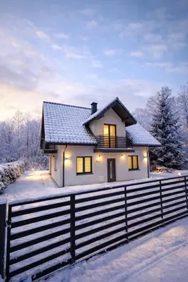 a white house with a fence in the snow at Pod Łopieniem z Sauną i Balią in Tymbark