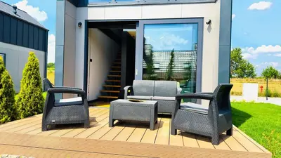 a deck with three chairs and a table at Green Garden Zielonki 14e in Bibice