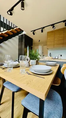 a wooden table with plates and glasses on it in a kitchen at Green Garden Zielonki 14d in Bibice