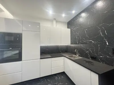 a kitchen with white cabinets and a black marble wall at Pawlikowskiego nest - 5 minutes walk to Main Square in Kraków