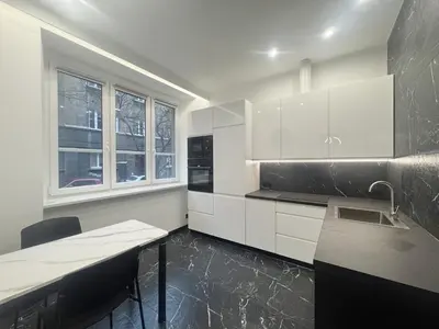 a kitchen with white cabinets and a sink and a table at Pawlikowskiego nest - 5 minutes walk to Main Square in Kraków