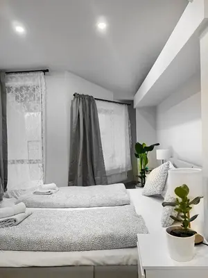 a white bedroom with two beds and a window at Spacious Apartment with 5 bedrooms and 2 bathrooms for 12 guest in Cracow Old Town in Kraków