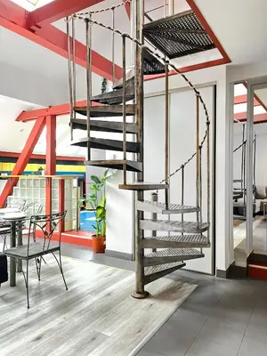 a metal spiral staircase in a room with a table at Spacious Apartment with 5 bedrooms and 2 bathrooms for 12 guest in Cracow Old Town in Kraków