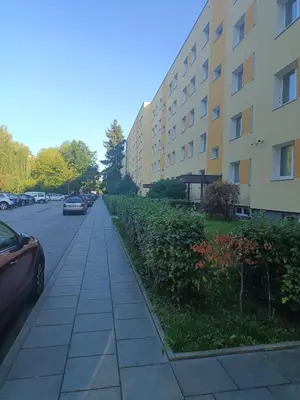 a sidewalk next to a building with cars parked at CityLink Studio - Free Public Parking in Kraków