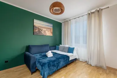 a living room with a blue couch and a window at Tauron Arena Homely Apartment by BookingHost in Kraków